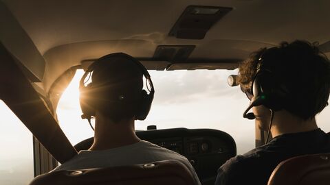 Fluglotse Zwei Männer sitzen in einem Flugzeug mit Headset auf.